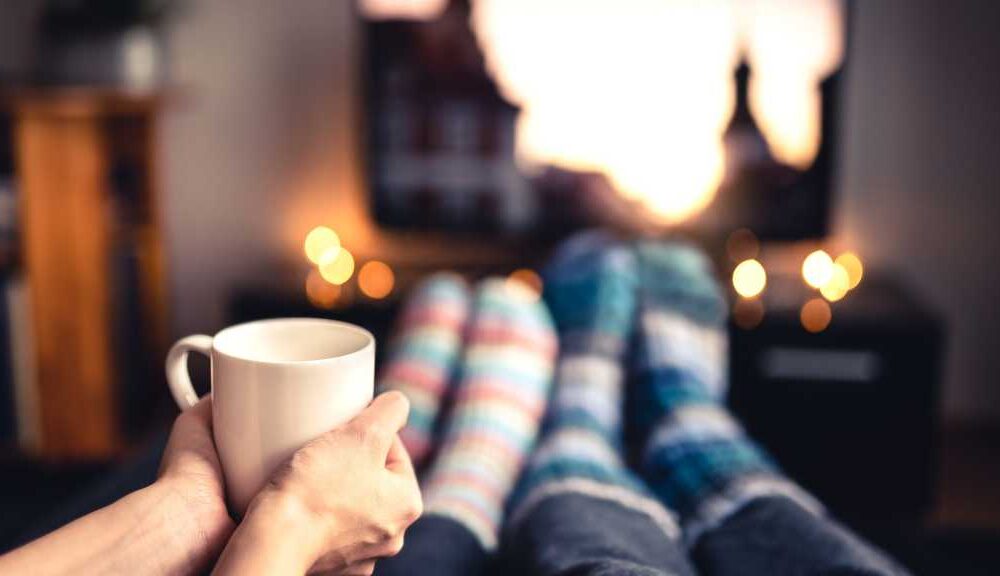 Two people in cosy socks watching TV with a cup of coffee