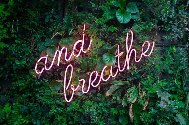 A neon sign saying "and breathe".