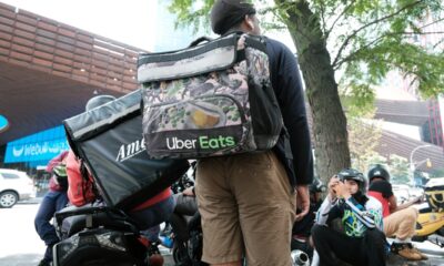 App-based delivery workers wait outside of a restaurant that uses app deliveries