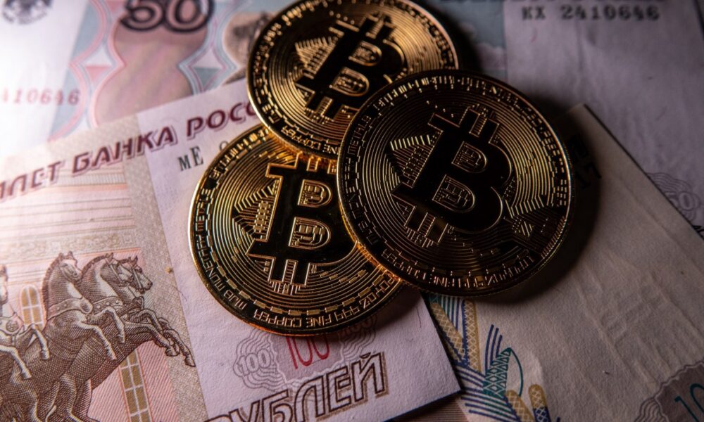 Novelty Bitcoin tokens are photographed besides Russian rouble bank notes.